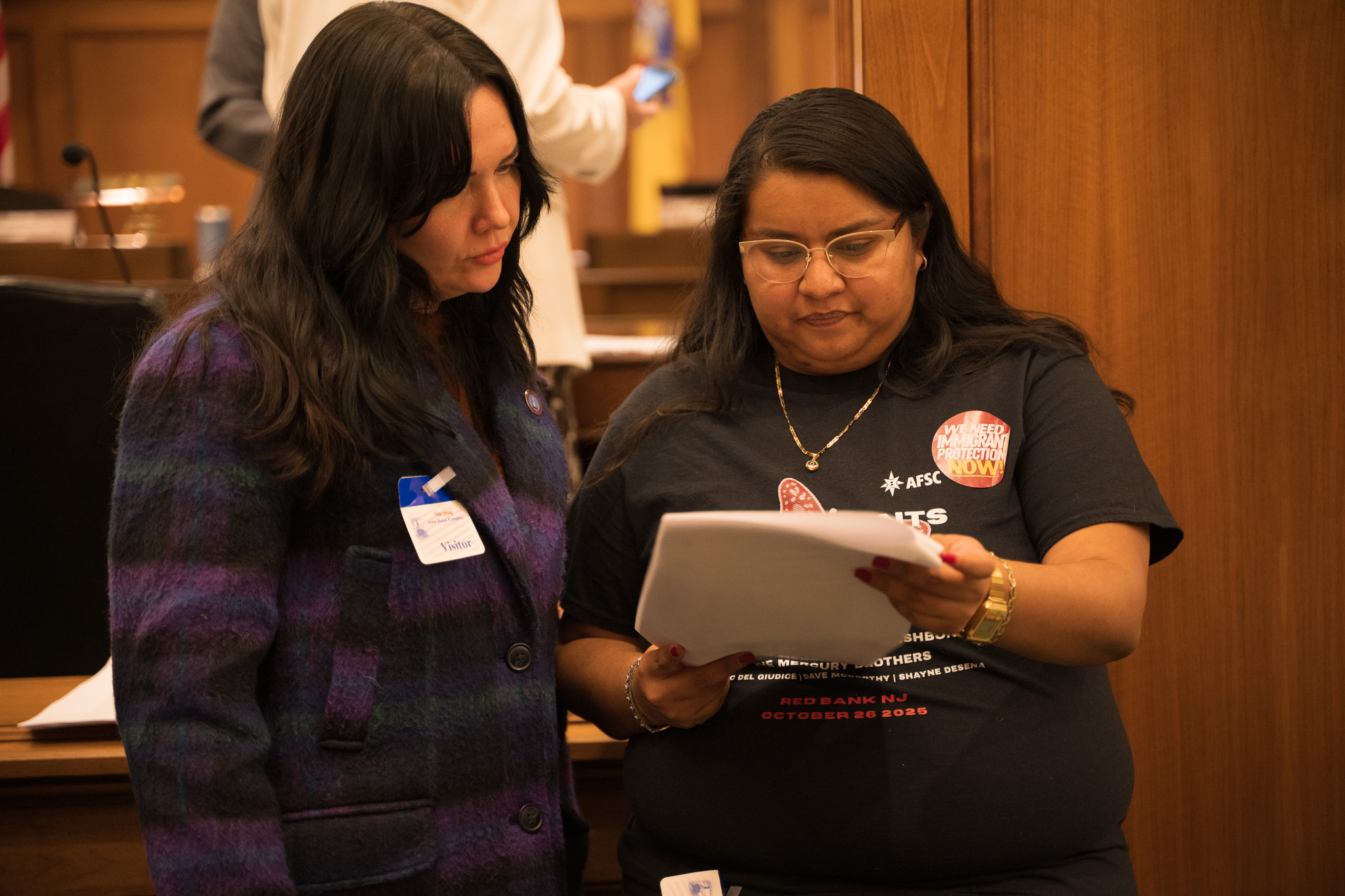 two people stand together looking at a document