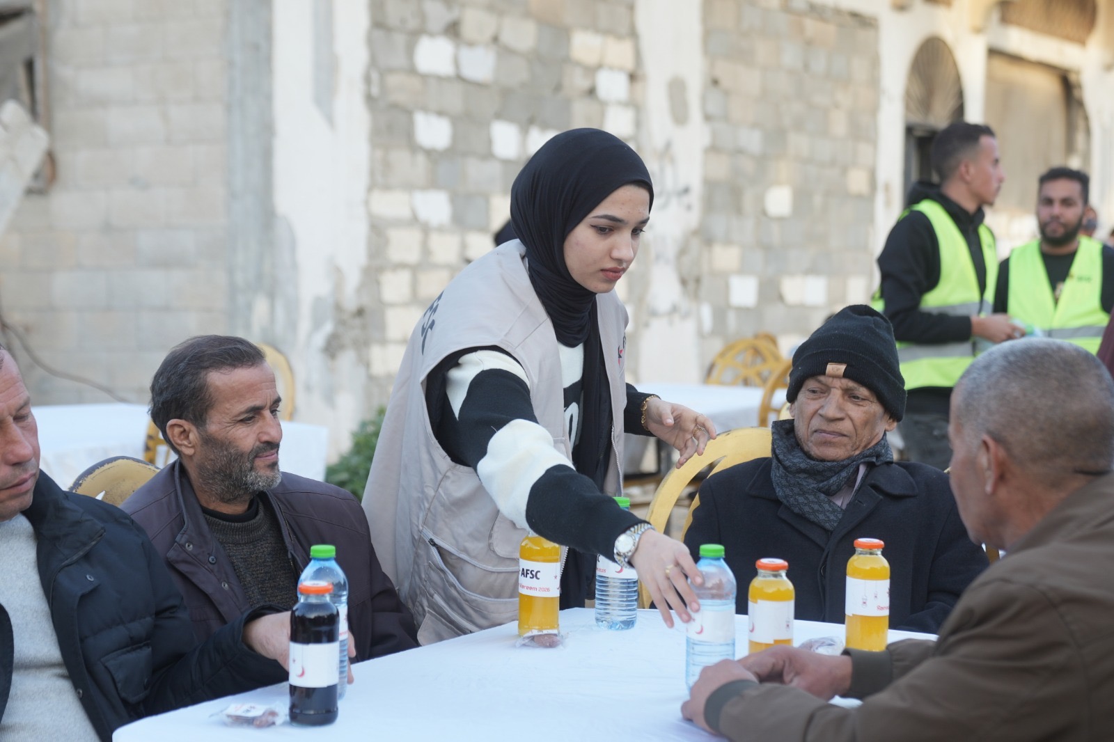 Woman serves bottles of juice and waters to people sitting at a table