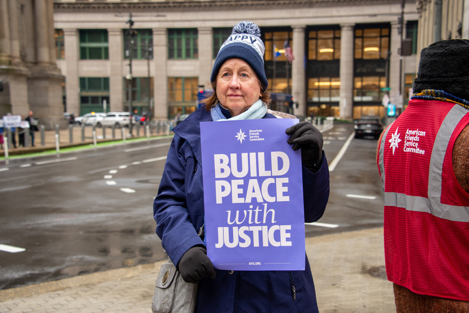 A woman holds a sign that says Build Peace with Justice