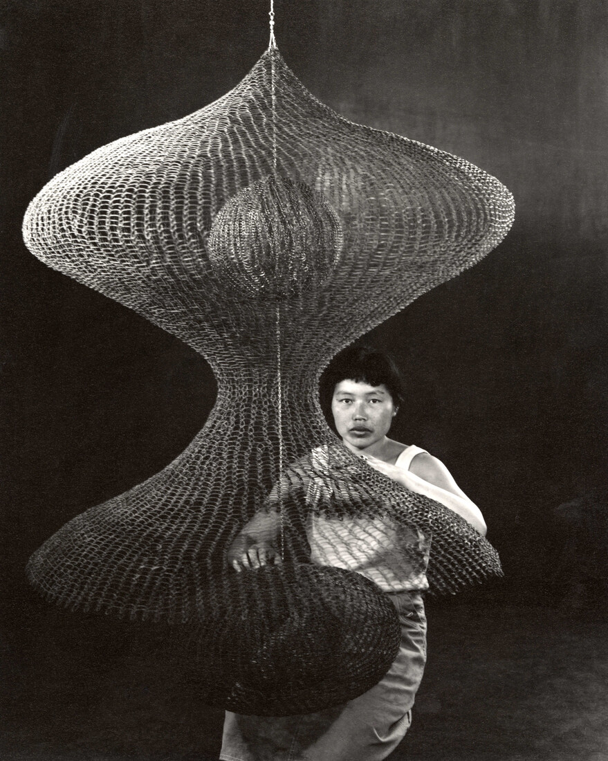 ruth asawa kneeling behind a hanging looped-wire sculpture, 1957