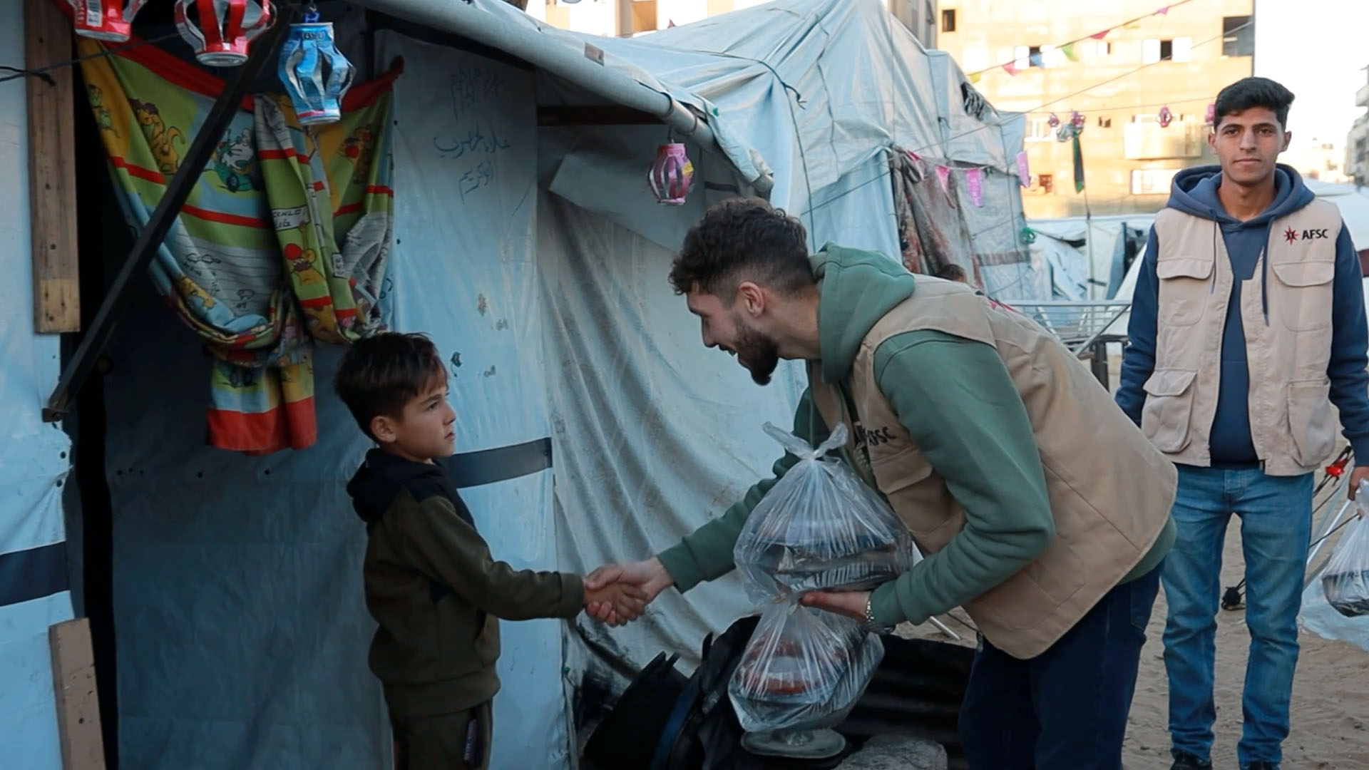 Man shaking the hand of a young child as he offers a package of food