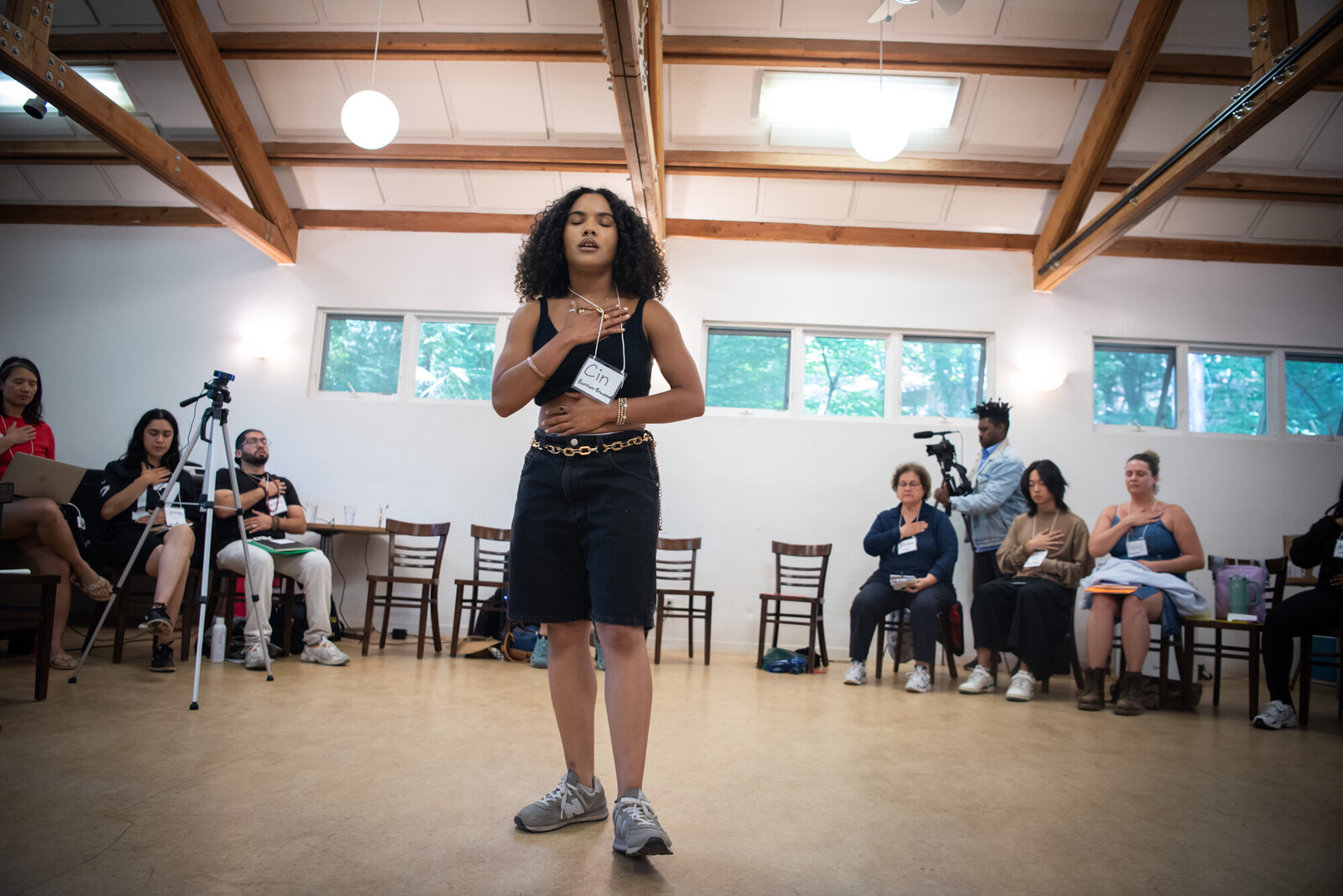 person guiding a group standing up in the middle of a circle their hands are over their heart