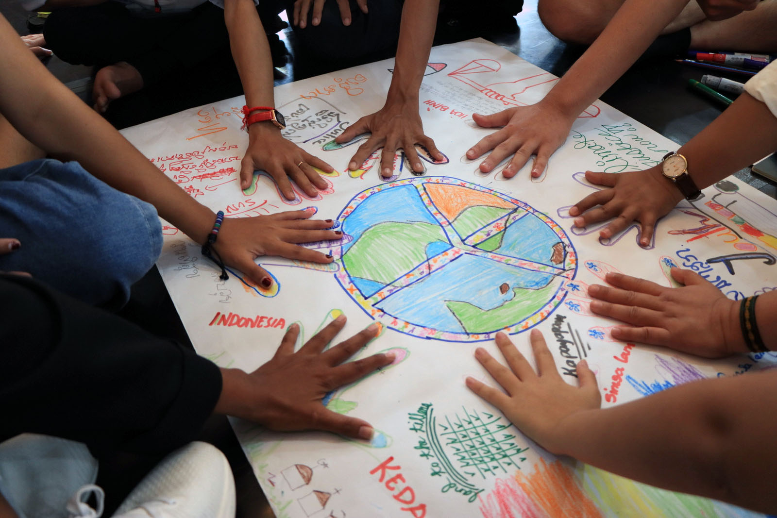 photo of youth with hands around a drawing of the world