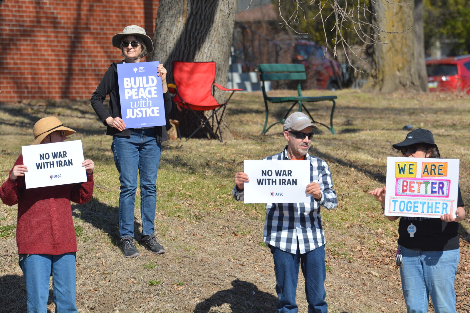 group of four people protesting holding various signs one says no war with iran