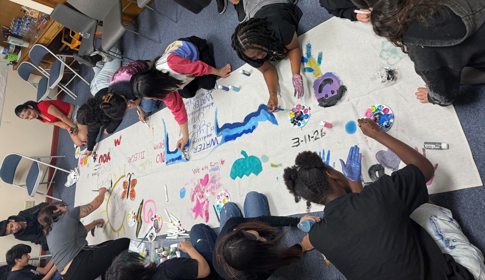 Middle school youth work on a collective banner making project.