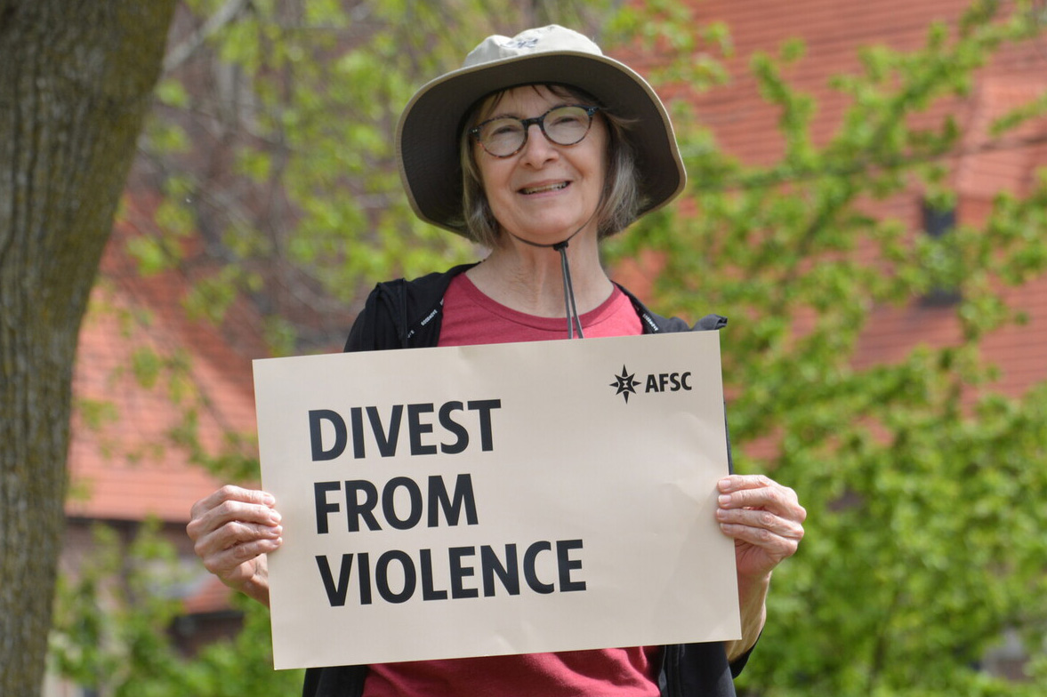 Woman holding a sign that reads 'Divest From Violence'