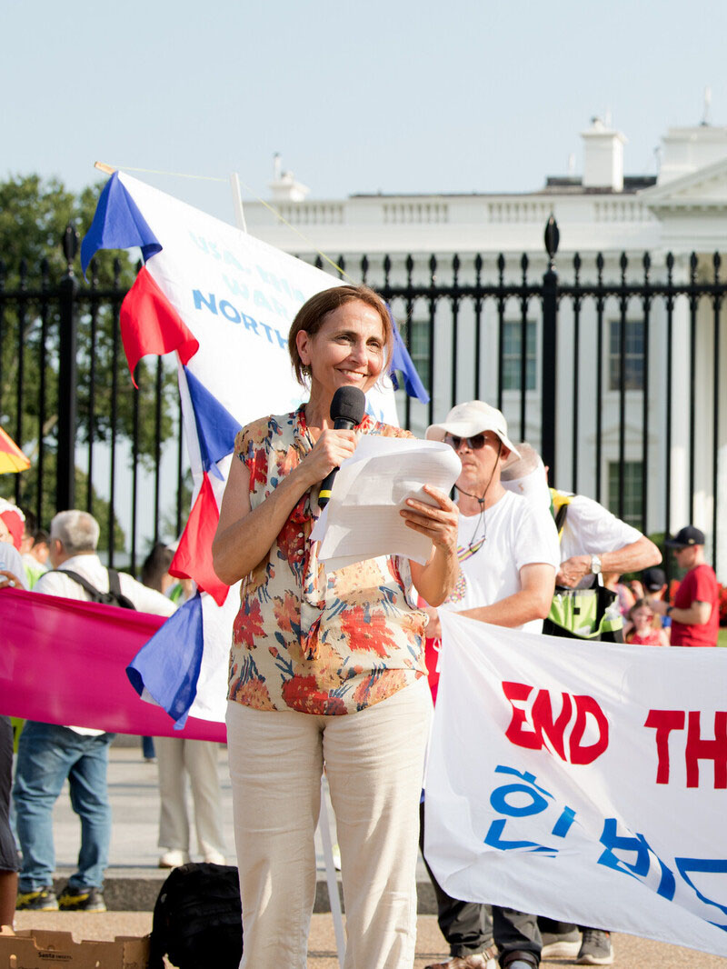 photo of joyce outside of a capitol building holding a mic and reading from a paper