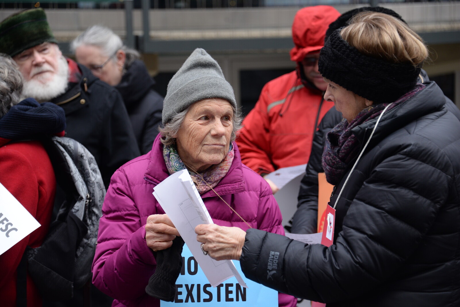 woman handing another woman a piece of paper love as action rally