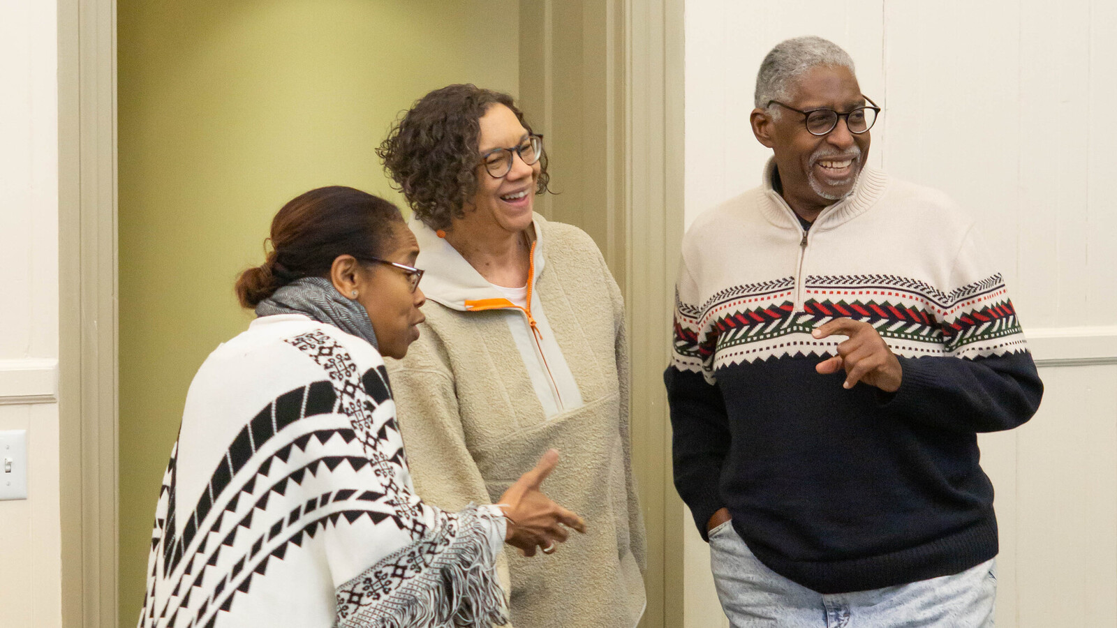 three people laughing in a white painted room at keith's retirement party