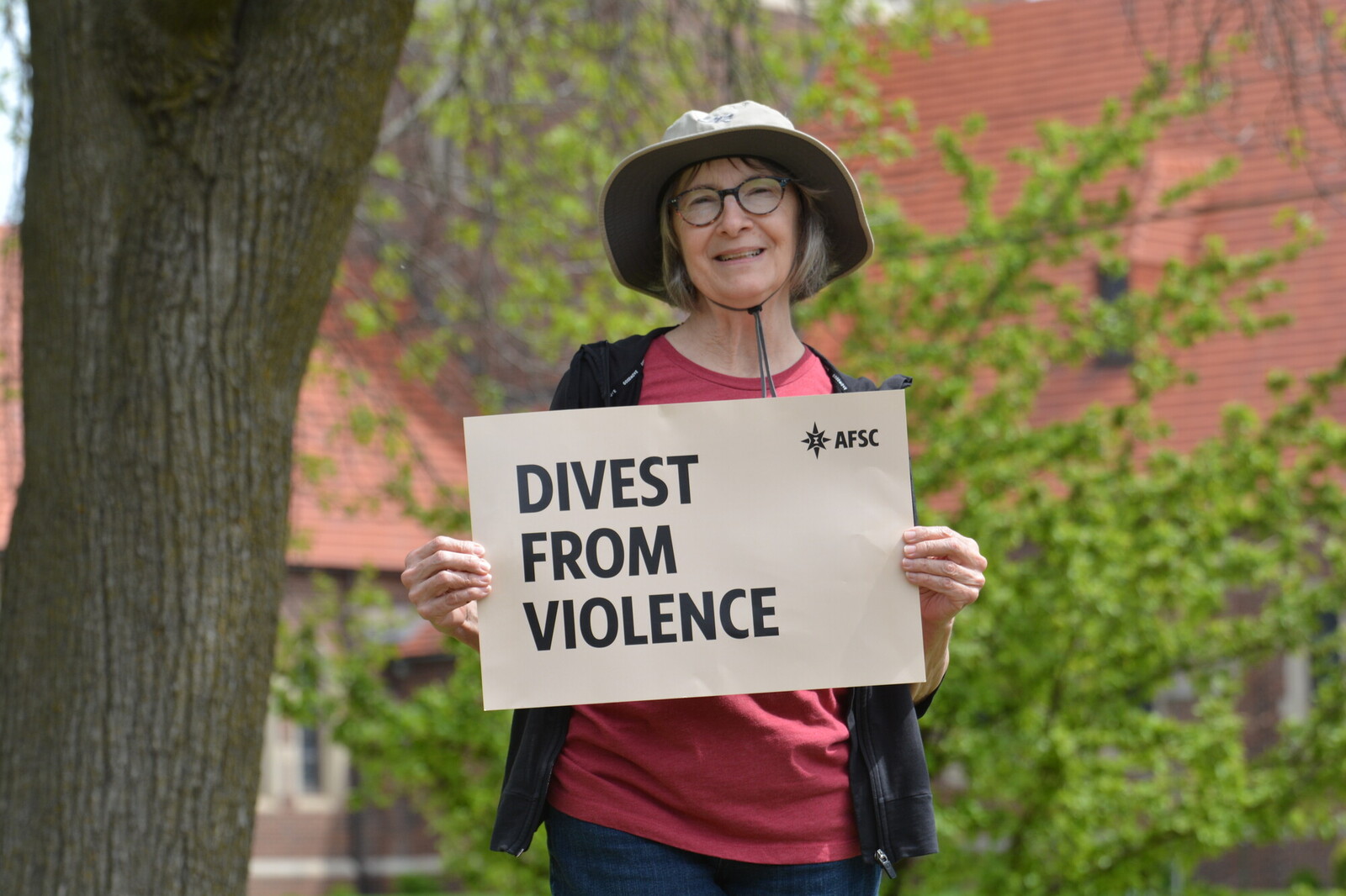 photo of a woman in a sun hat holding a sign that says 