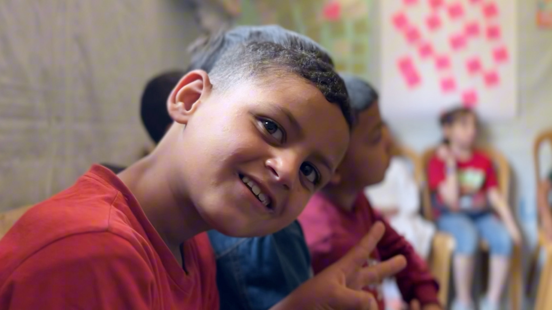 A young child smiles at the camera in a newly-restored learning center