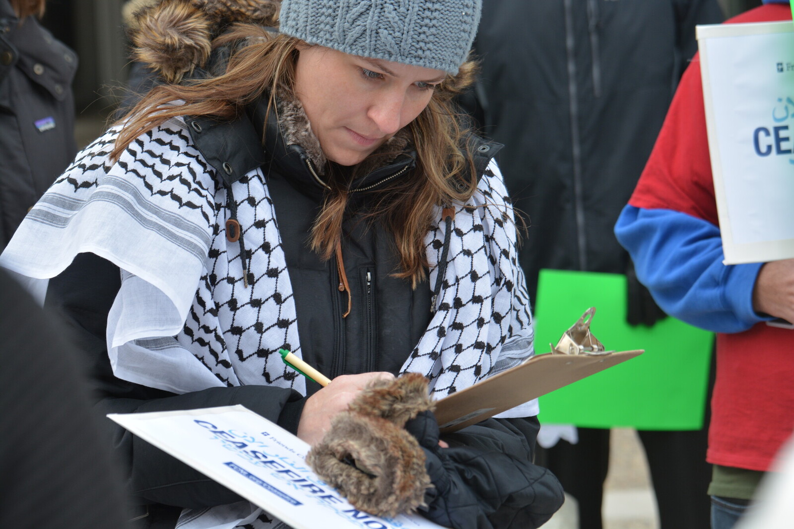someone wearing keffiyeh signing a petition