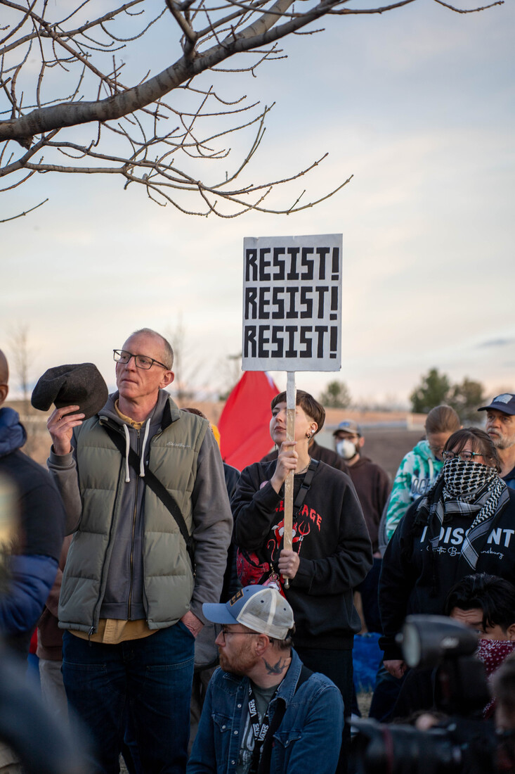 people at a rally holding resist protest sign