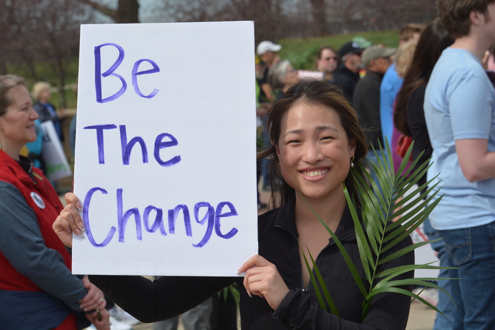 A woman holds up a palm leaf and a sign that reads, 