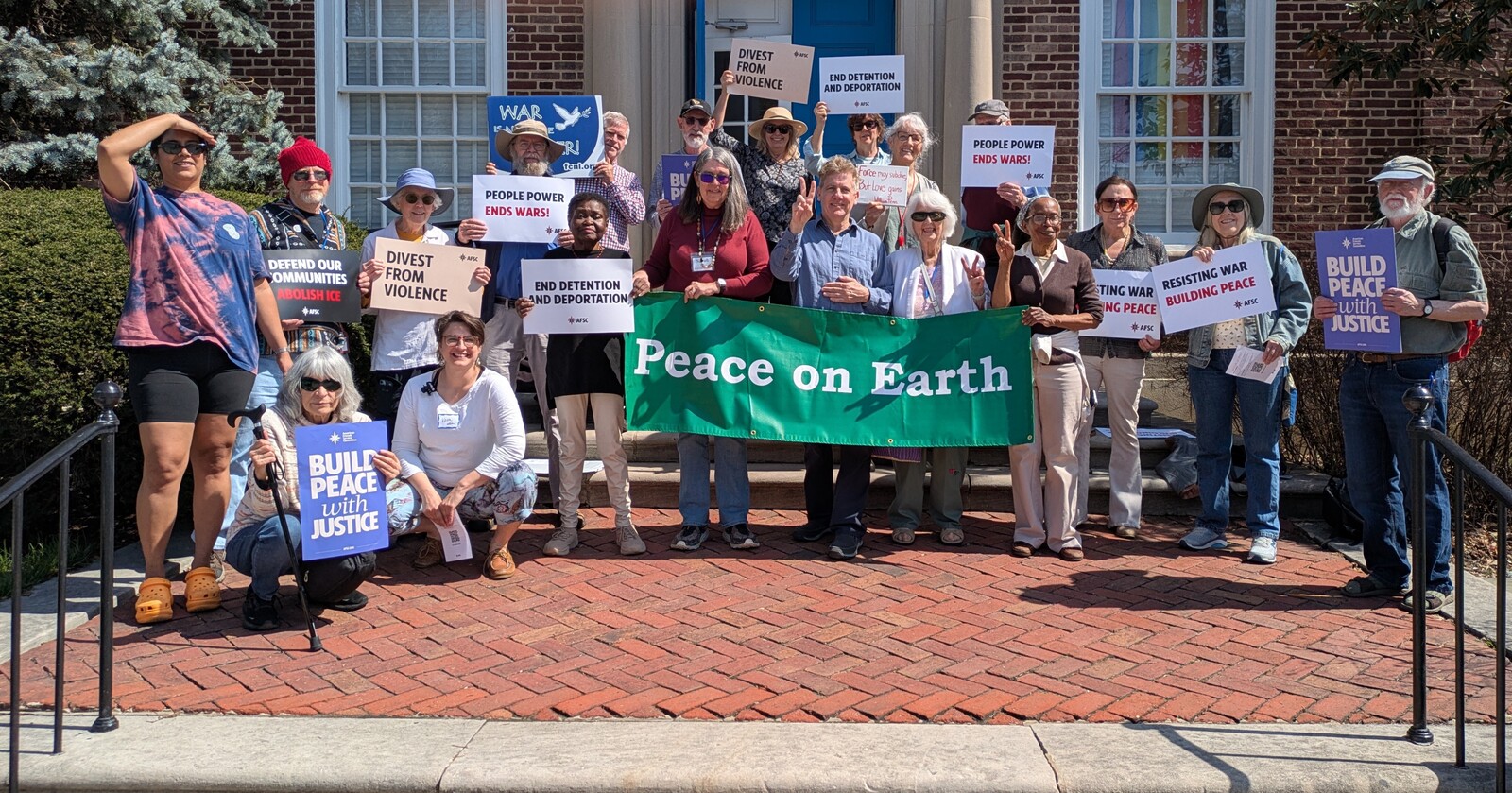 Friends gathered in front of a Quaker meeting house in Baltimore, holding signs with messages of peace