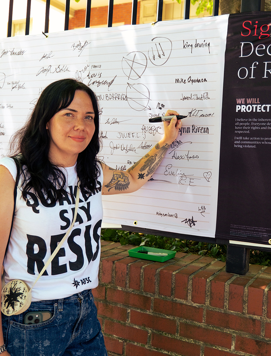 woman with sharpie signing a large declaration banner