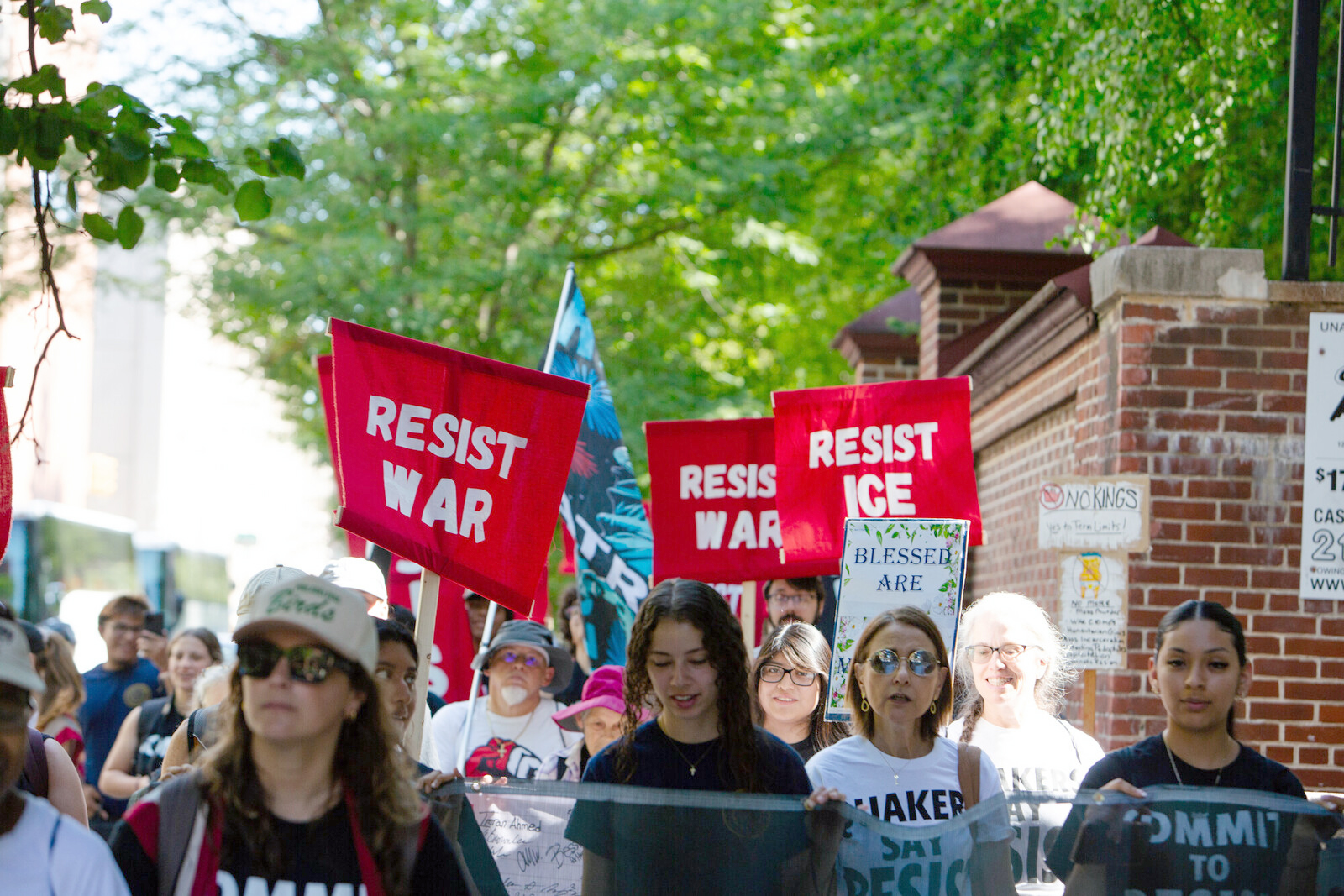 People walking in a protest holding signs that say resist war
