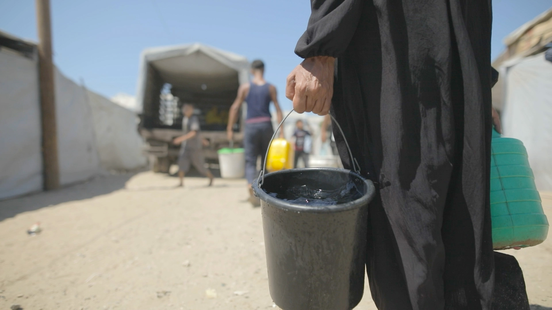 A woman carries a full bucked of water