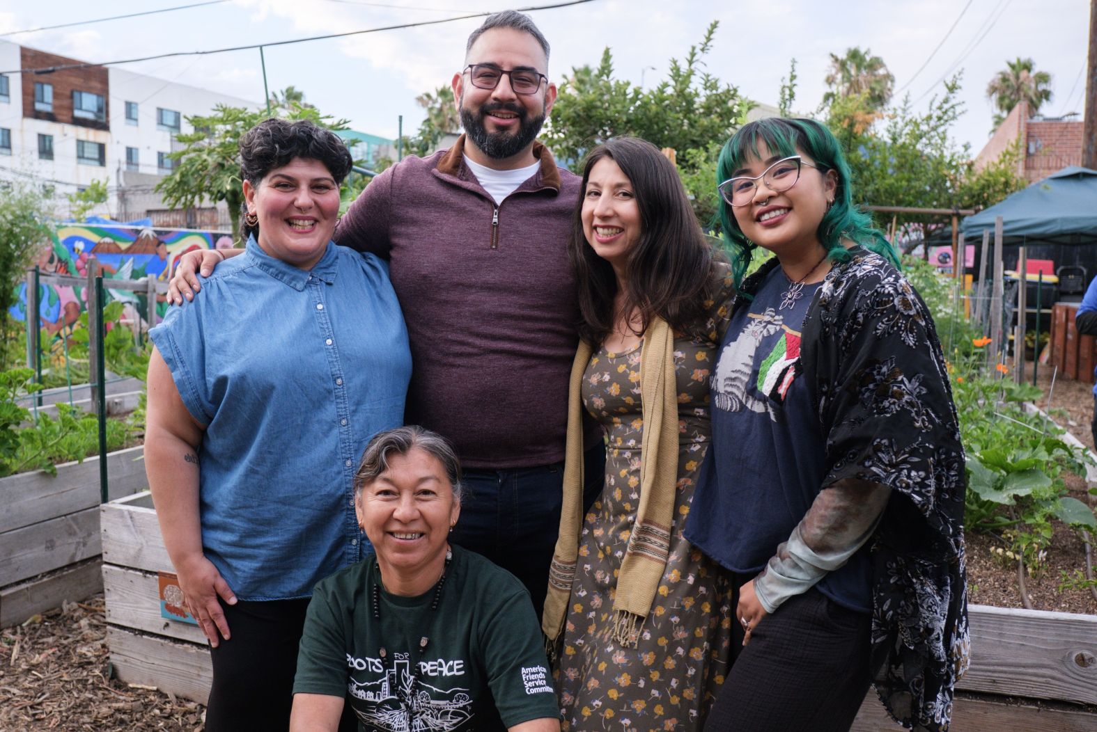 A group of five smiling in a community garden