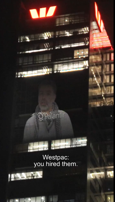 Projection of man criticizing Westpac's collaboration with Palantir on the side of the Westpac office in Australia
