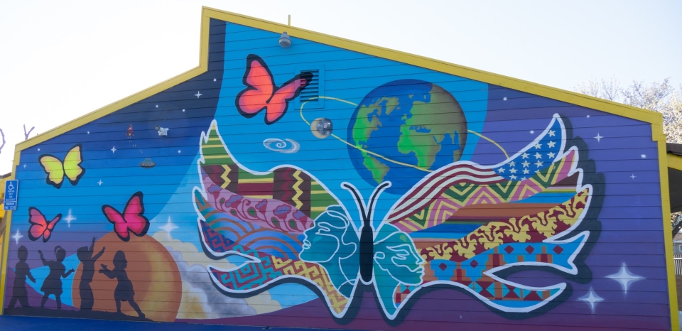 Hana's mural depicts the earth, a big blue butterfly, and the silhouettes of children playing.