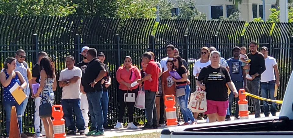 People wait in long line around fence