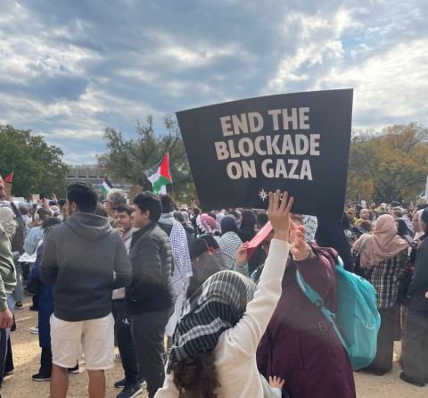 Child holding a sign at a protest saying "End the blockade on Gaza"