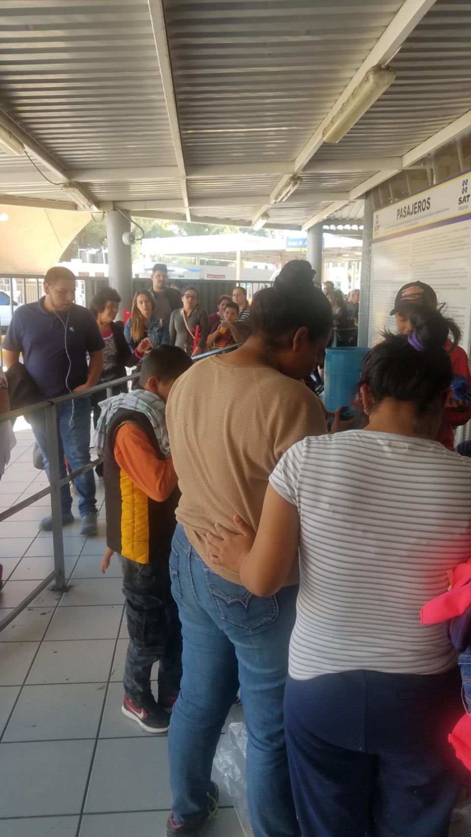 At the Nogales port of entry, commuters and travelers look on as migrant families gather together as they wait  for their turn to present themselves to CBP. Photo: Jody Mashek/AFSC 